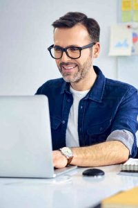 Casual businessman working on laptop at desk in office