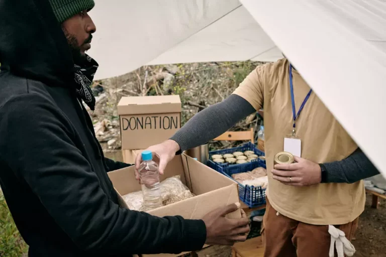 young-refugee-man-holding-box-while-volunteer-putt-2021-10-20-03-17-47-utc