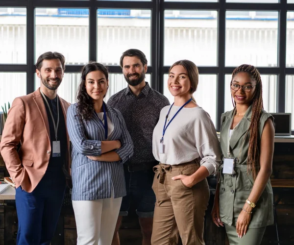 Portrait of young businesspeople standing indoors in office, looking at camera
